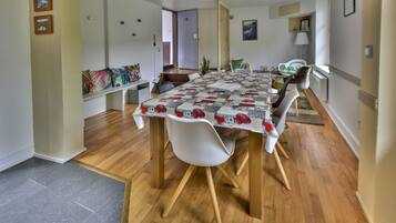 A dining area with a table covered by a patterned tablecloth, surrounded by chairs with wooden legs.