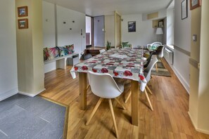 Ein Essbereich mit einem Tisch, der mit einer blumigen Tischdecke bedeckt ist, umgeben von Stühlen.