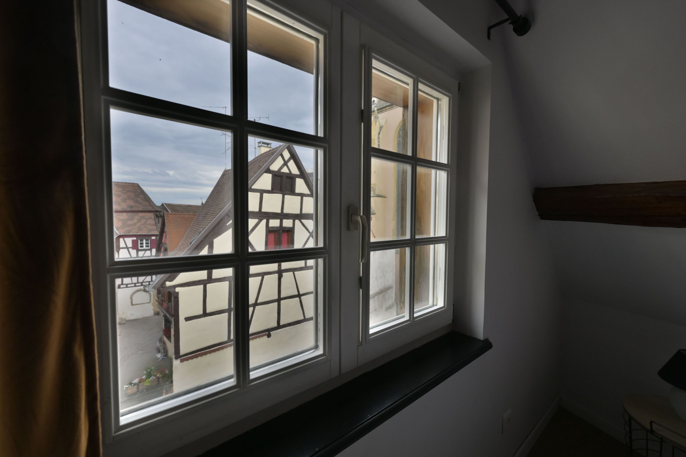A room with a large window overlooking a traditional half-timbered house.