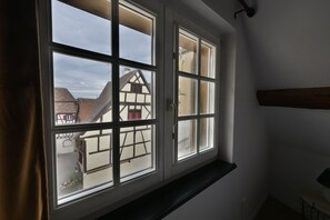 Ein Zimmer mit großem Fenster und Blick auf ein traditionelles Gebäude mit freiliegenden Holzbalken.