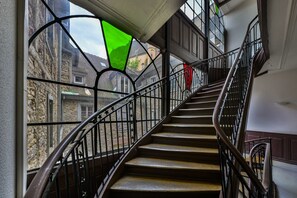 A staircase with metal railings and a view of old buildings outside.