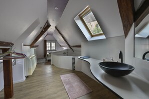 Eine moderne Küche mit Oberlicht, Holzbalken und einer großen, schwarzen Schüssel als Spüle.