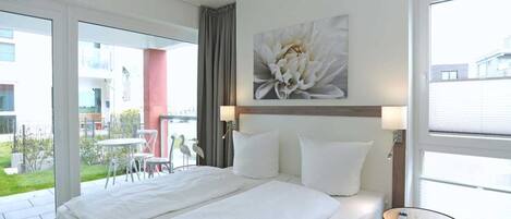 Een hotelkamer met een groot bed, een tafeltje en uitzicht op het buitengebied.