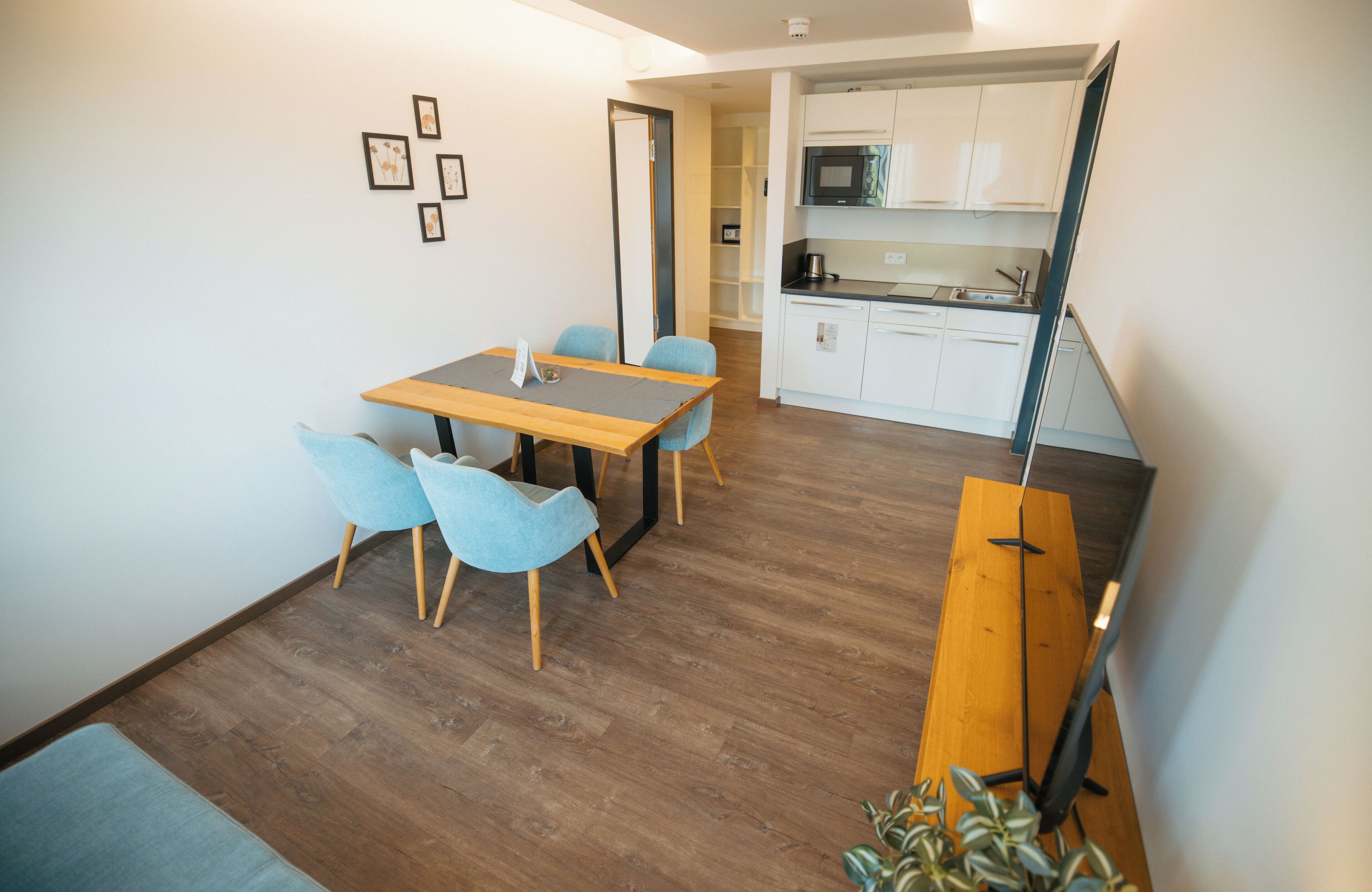 Un espacio habitable compacto con comedor, kitchenette y una escalera.