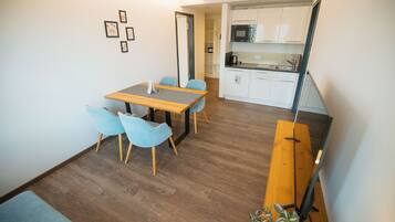 Un espacio habitable compacto con comedor, kitchenette y una escalera.