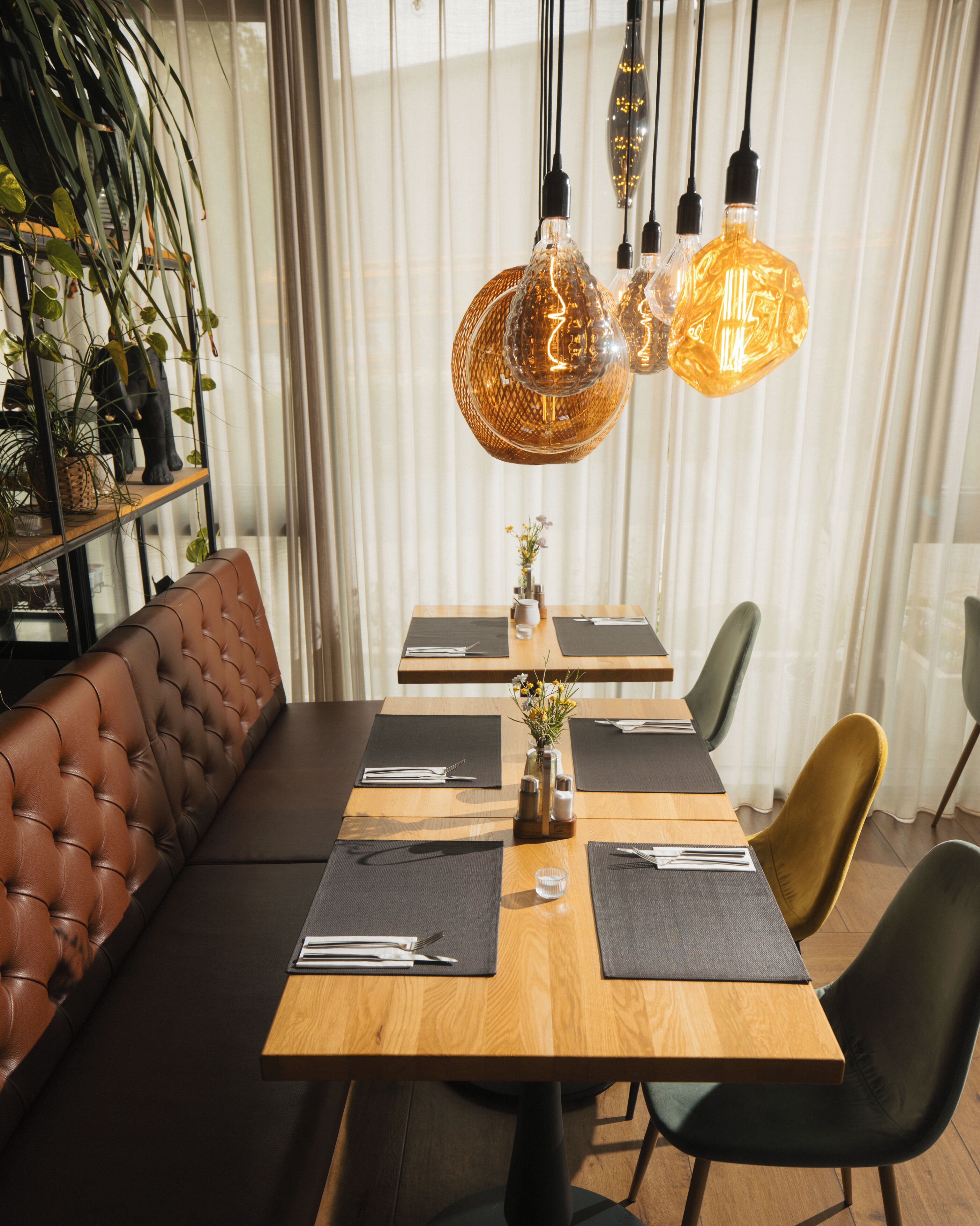 A dining area with a wooden table, black placemats, and a brown leather bench.