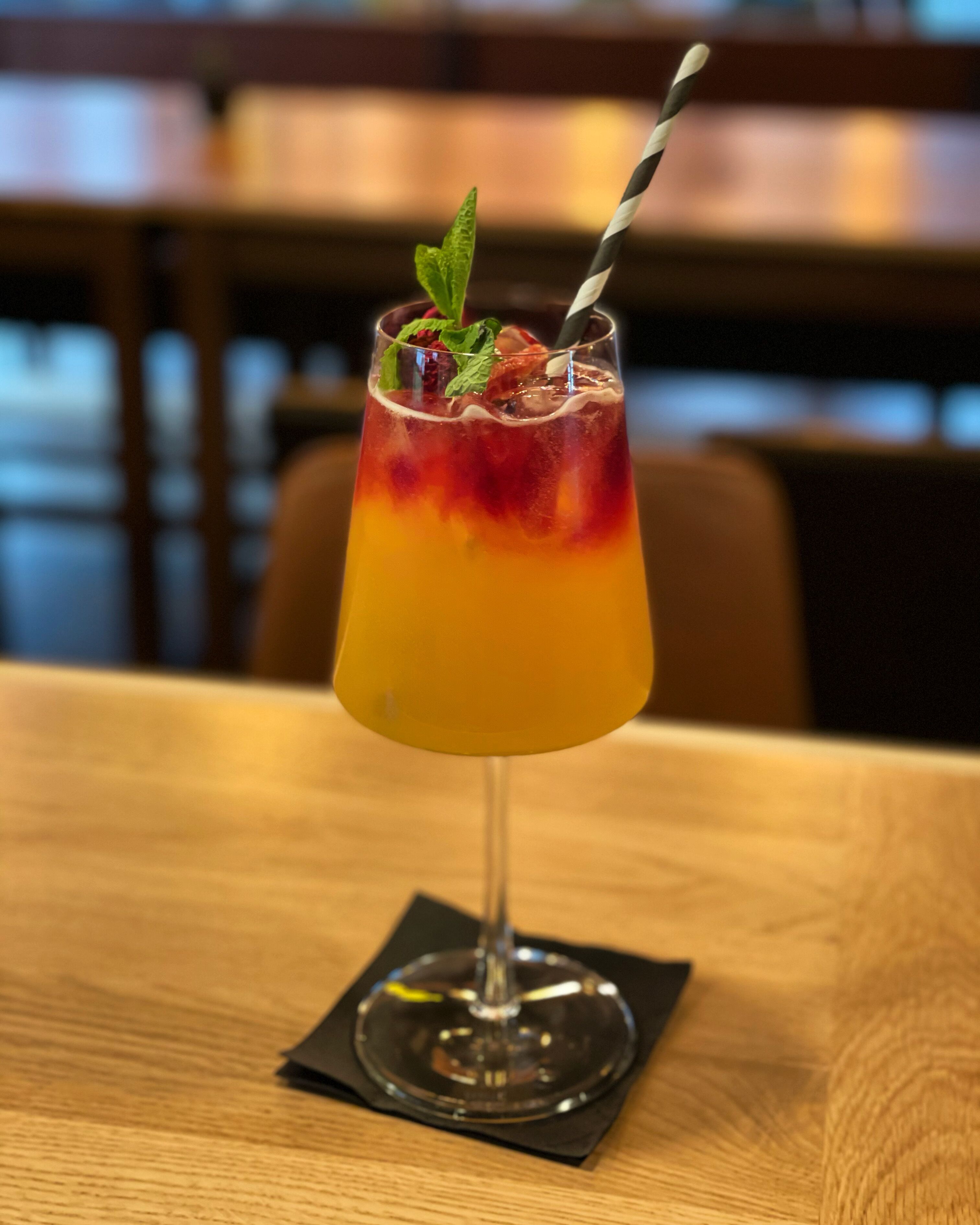 Ein Cocktail in einem Stielglas auf einem Holztisch.