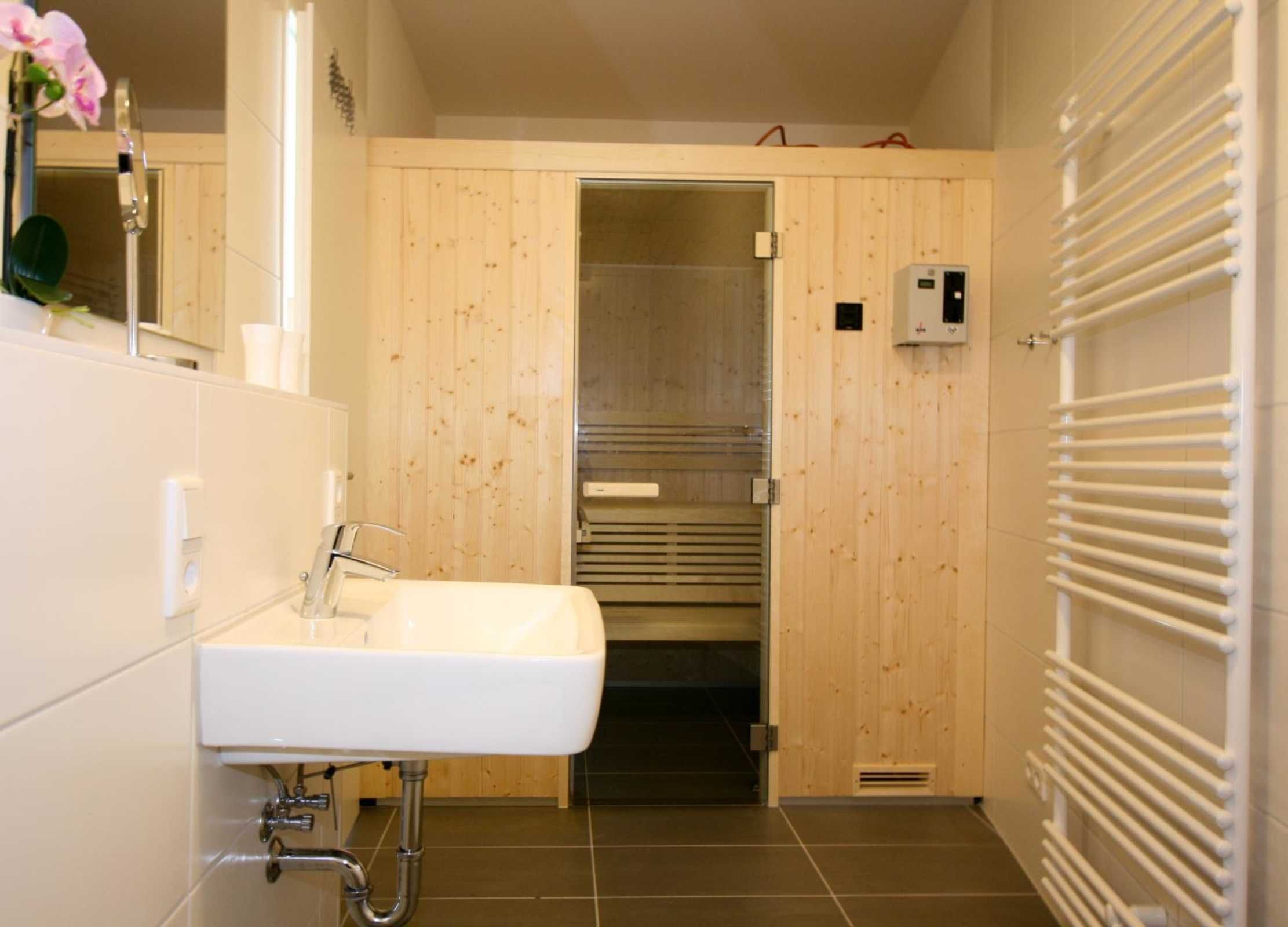A bathroom with a white sink, wooden walls, a towel rack, and a shower area.