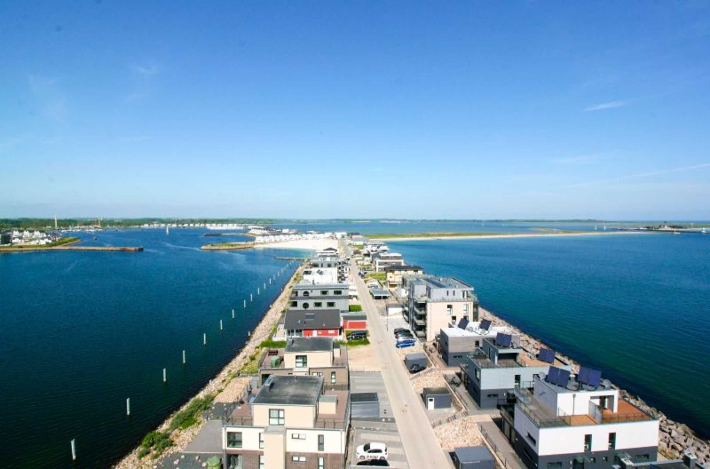 A coastal hotel with modern architecture, a marina, and a clear view of the sea.