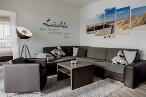 Ein modernes Wohnzimmer mit Ecksofa, Couchtisch und Stehlampe.