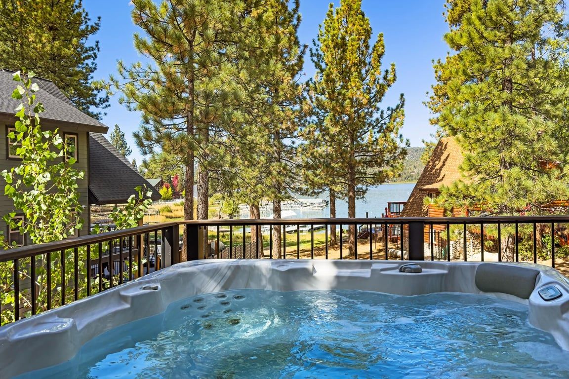A hot tub surrounded by trees and a view of a lake.
