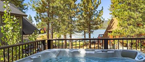 A hot tub surrounded by trees and a view of a lake.