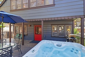 A deck with a hot tub, outdoor seating, and a red door. - Rustic Lakefront! PET FRIENDLY! Boat Dock! Pool Table! HOT TUB! (Big Bear Lake)