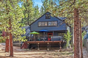 Une cabane dotée d’une terrasse, entourée d’arbres.