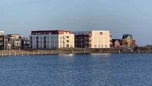 Una propiedad frente al agua con edificios modernos, un muelle de piedra y una vista despejada del agua.