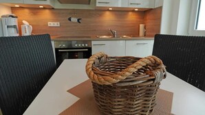 Une cuisine moderne avec des armoires blanches, une hotte de cuisinière en acier inoxydable et un four encastré.