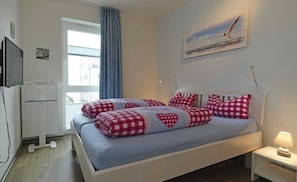 A bedroom with a bed, a window, a painting, and a bedside lamp. - BOW-1.08, 4 pers., 55-65sqm (HT) - Residence Bollwark 1.0 (Kappeln)