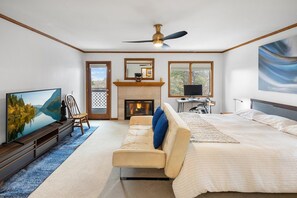 A bedroom with a bed, a sofa, a TV, a fireplace, and a ceiling fan. - Central A/C! HOT TUB! Play on an Acre! Near Bear Mountain/Zoo/Golf/Hiking! EV Charger! Multi-Game Tables! (Big Bear City)