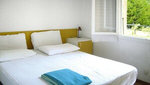 Ein Bett mit weißer Bettwäsche, ein blaues Handtuch und ein Nachttisch mit einer Lampe.