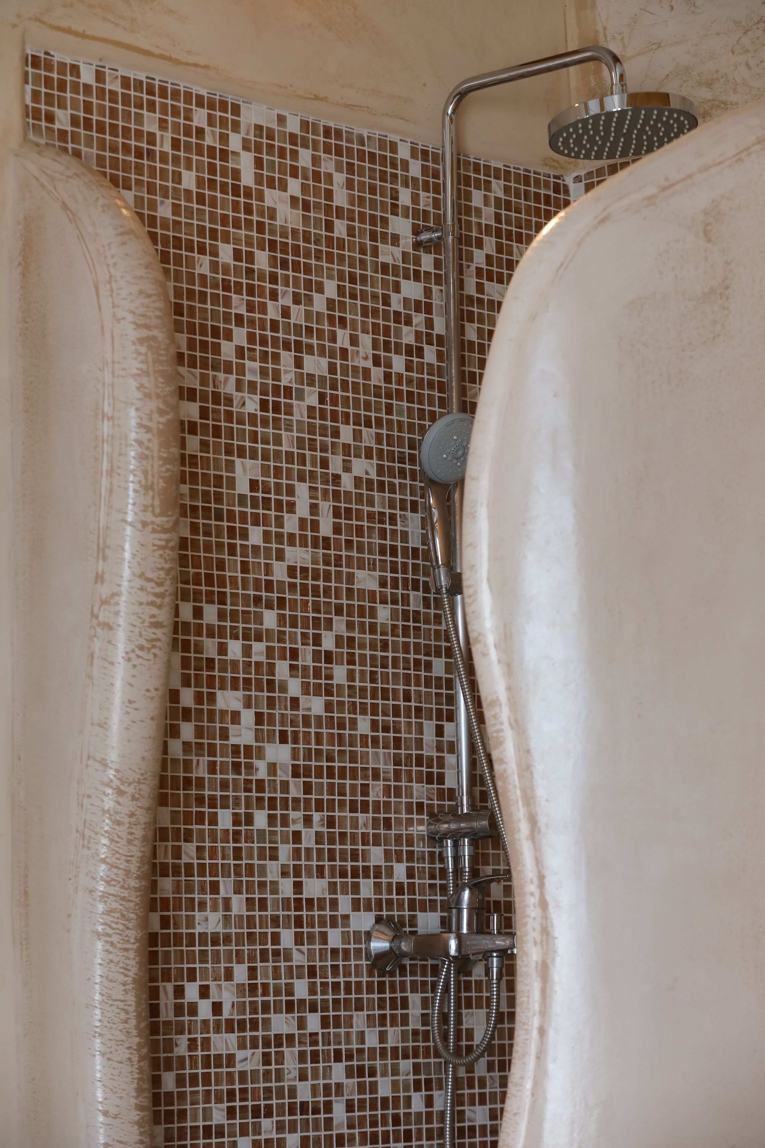Zona de ducha con pared de azulejos y cabezal de ducha.