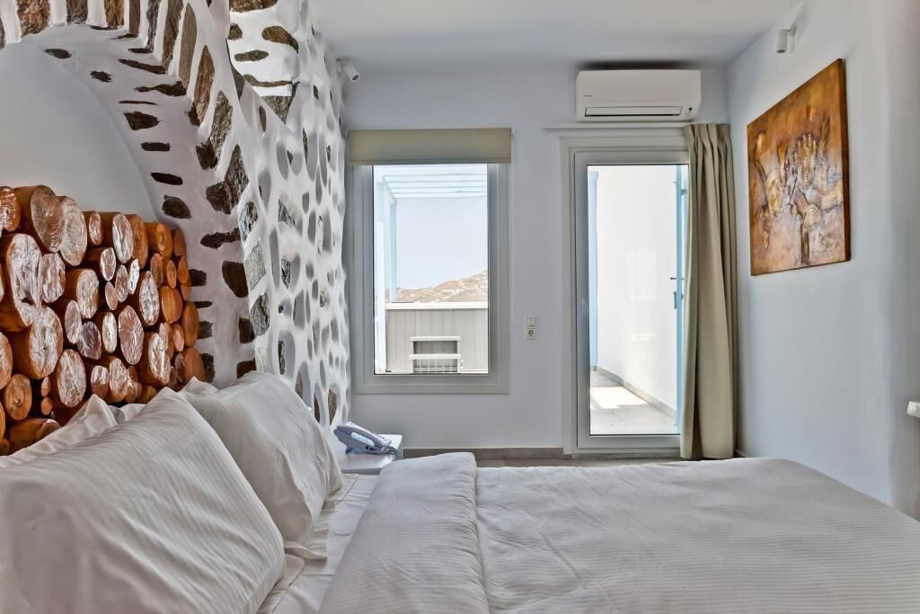Une chambre d’hôtel avec un lit, une fenêtre, un appareil de climatisation et un tableau au mur.