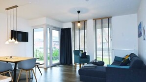 Een moderne woonkamer met een bank, stoelen, een eettafel en een televisie.