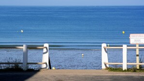 Une vue sur la mer, avec une rambarde et un panneau indiquant qu'il est interdit de se baigner.