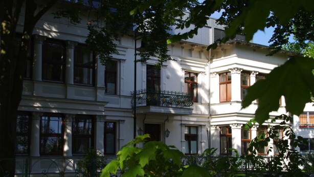 A multi-story building with classical architecture, featuring balconies and large windows.