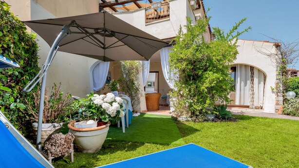 Un patio con una silla azul, una sombrilla grande y plantas en macetas.