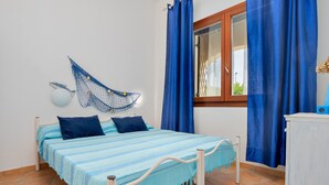 Un dormitorio con cama, cortinas, una ventana y una mosquitera en la pared.