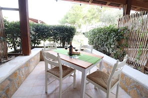 An outdoor patio with a table and chairs, surrounded by stone walls and greenery.