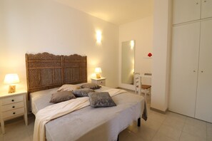 A bedroom with a bed, nightstands, a mirror, and a wardrobe.