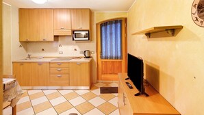 Eine kompakte Küche mit Holzschränken, einer Mikrowelle, einem Spülbecken und einem Fernseher auf einem Holzboden.