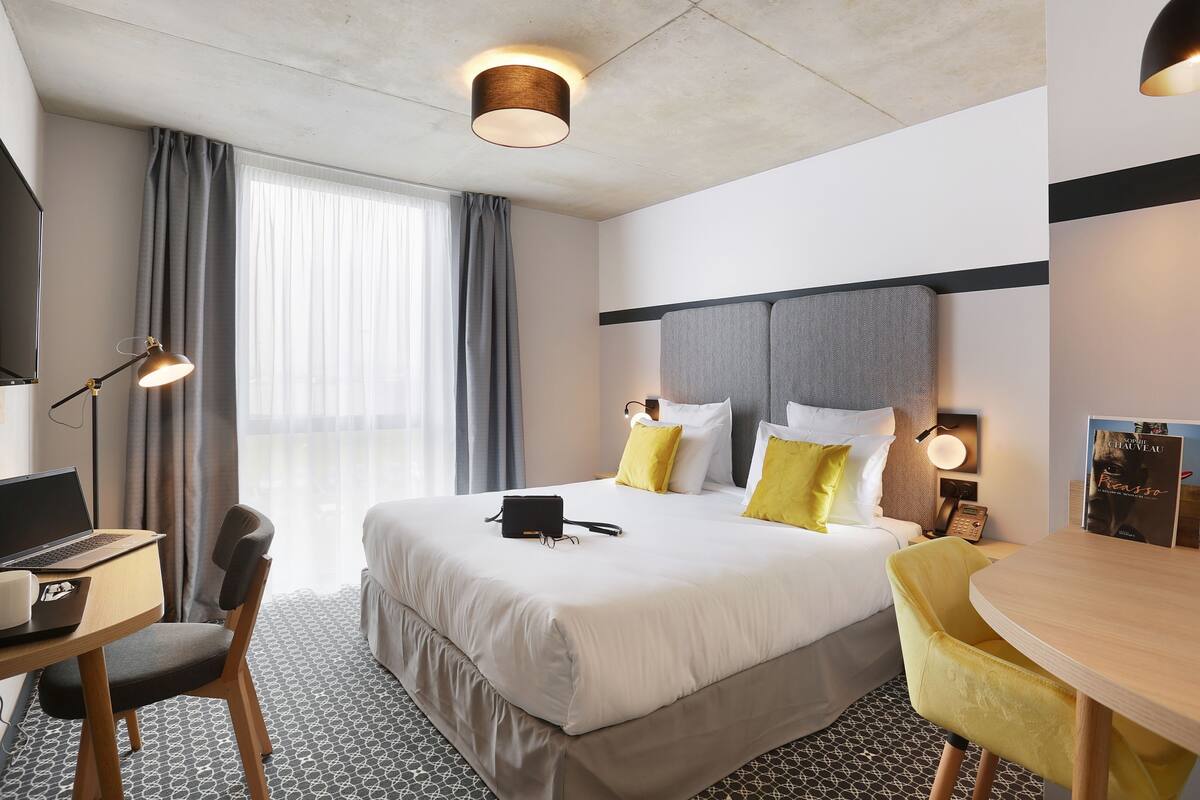 Ein Hotelzimmer mit Bett, Schreibtisch, Stuhl und einem kleinen Tisch.