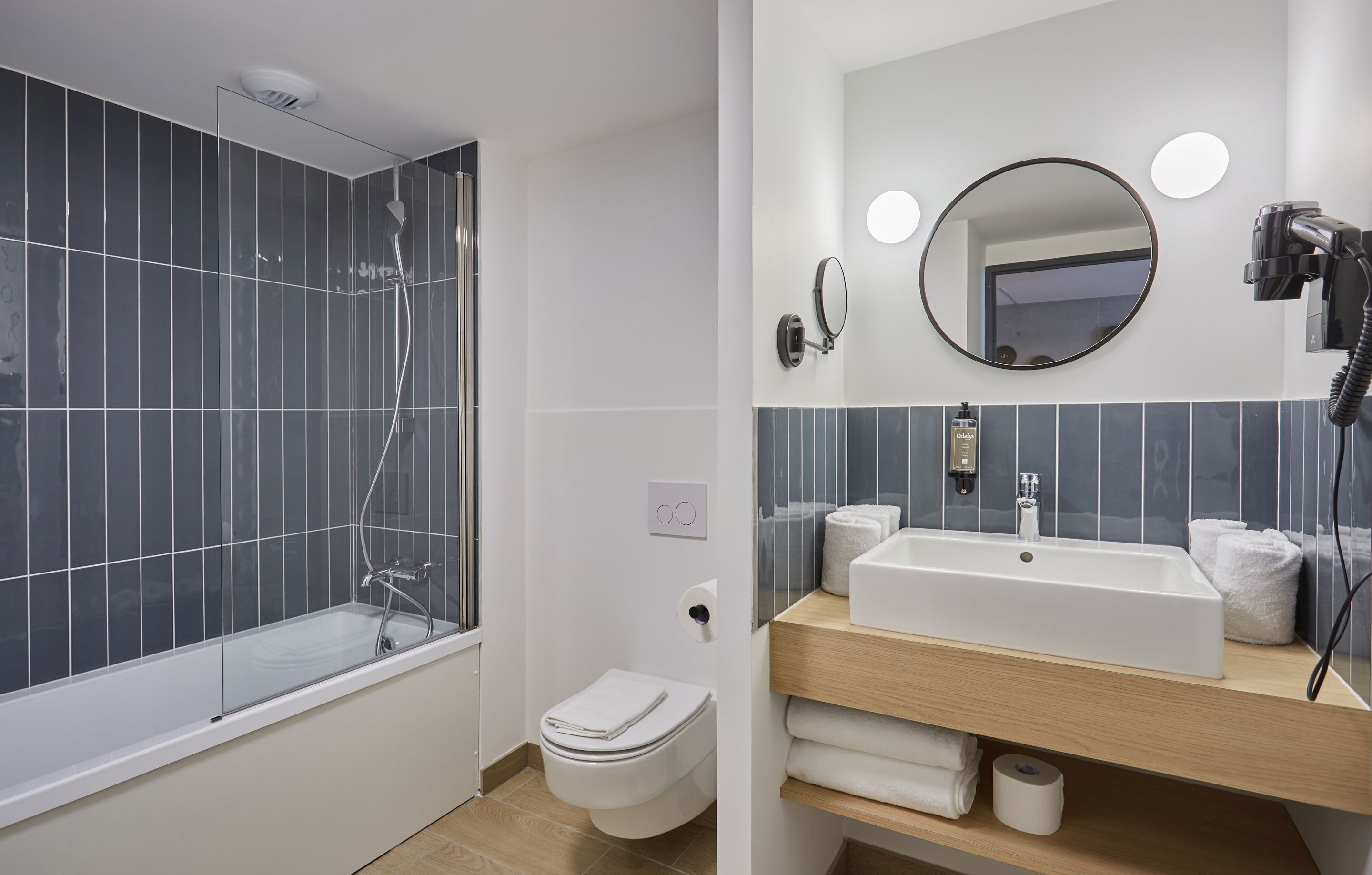 A modern bathroom with a bathtub, toilet, sink, and mirror.