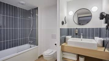 Een moderne badkamer met een badkuip, toilet, wastafel en spiegel.
