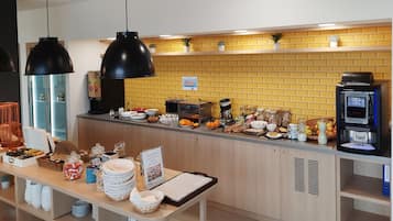 Una barra de desayuno con diversas opciones de comida, una máquina de café y un cartel que anuncia un desayuno feliz.