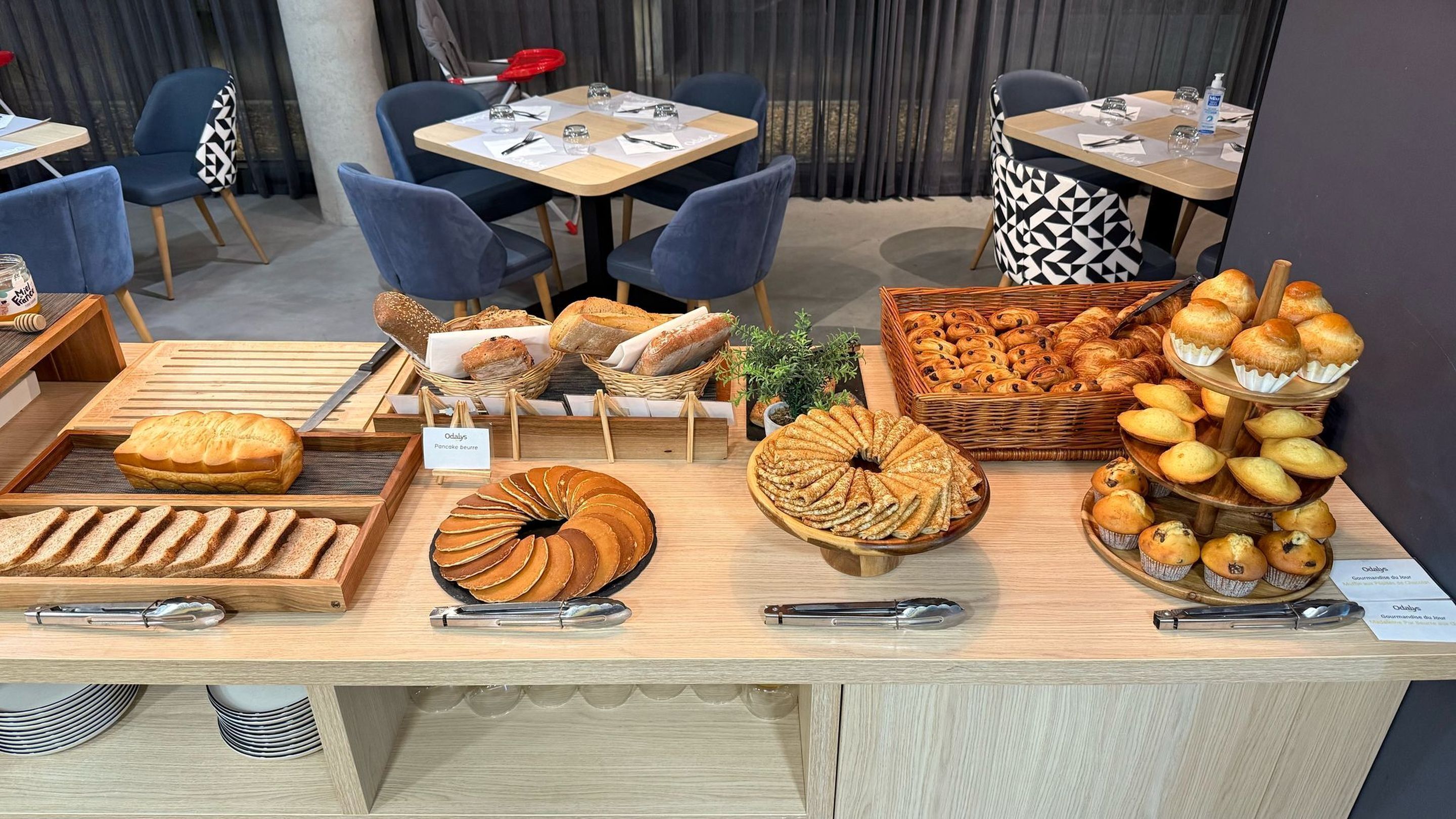 A bakery display with various breads and pastries, including a sign for 'Odalys Pancake beurre'.