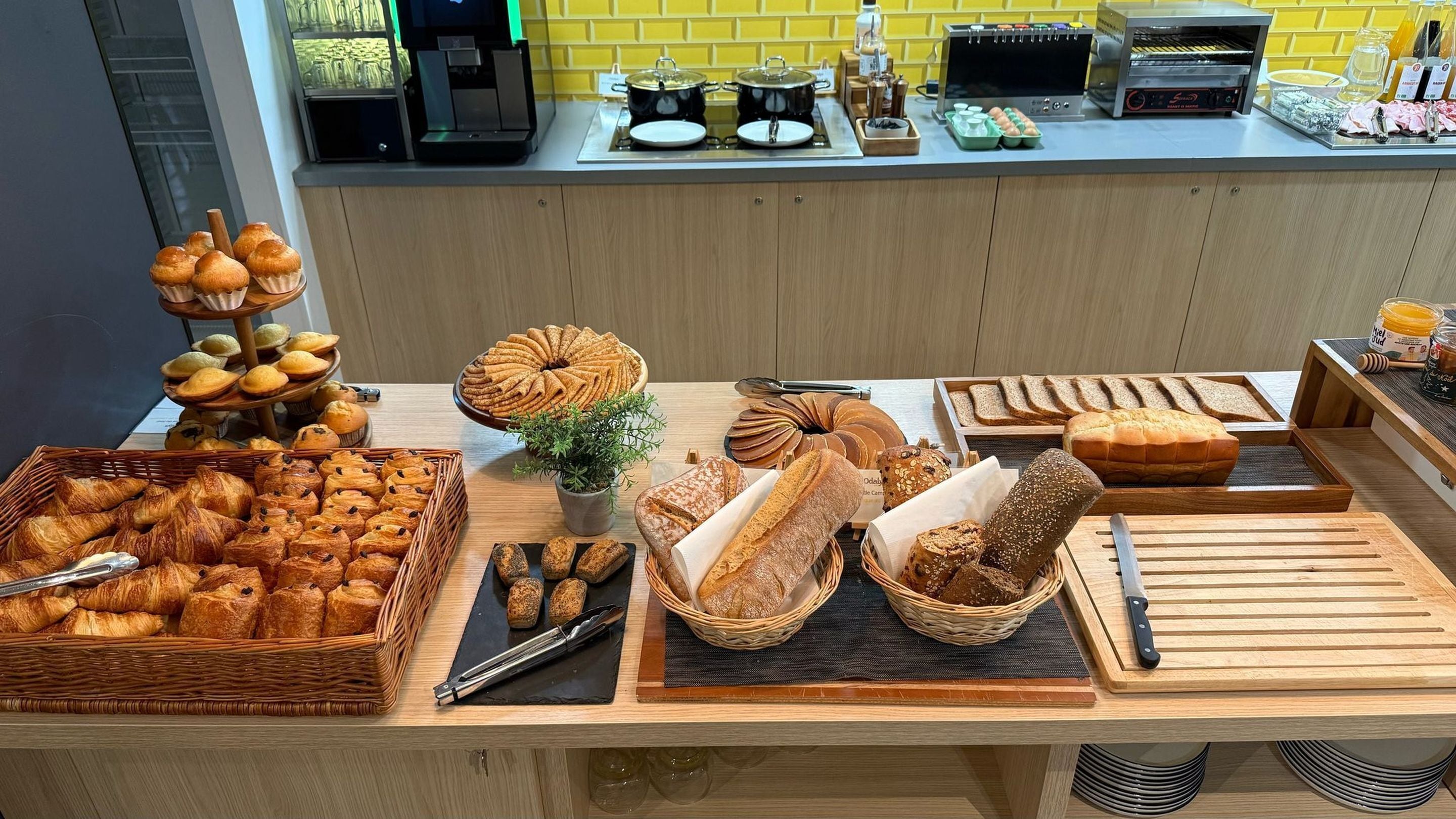 Un bufé de desayuno con panes, pasteles y una estación de café.
