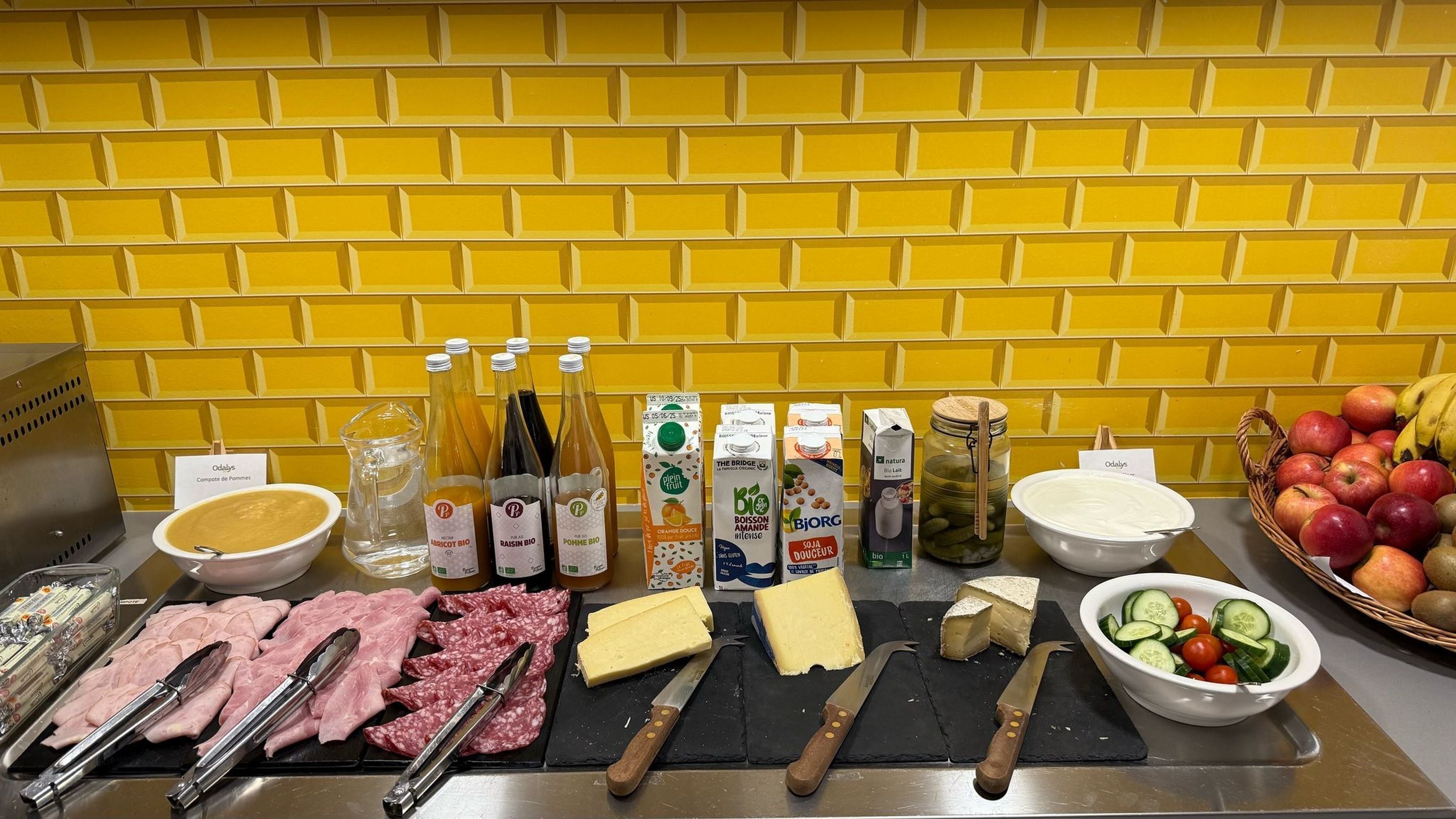 A buffet table with various food items including meats, cheeses, and beverages.