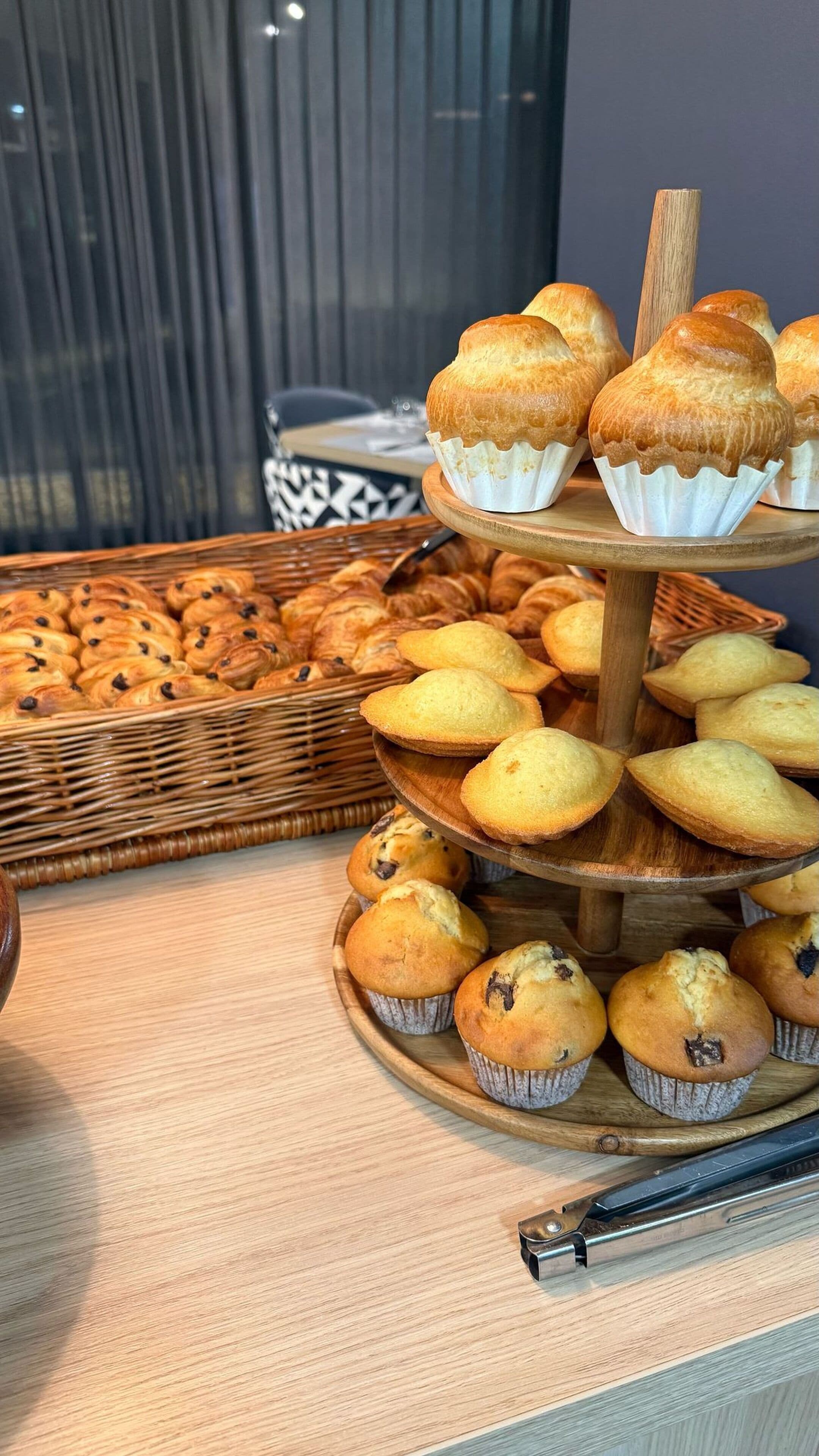 A display of muffins and pastries on a wooden stand.