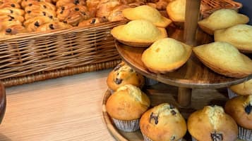 A display of muffins and pastries on a wooden stand.