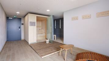 A modern interior with a wooden sauna, a small wooden bench, and a tiled floor.