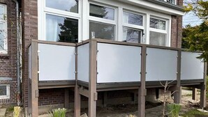 Ein Wohngebäude mit Ziegelaußenwand, großen Fenstern und einem Gartenbereich mit jungen Pflanzen.