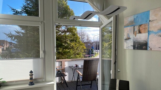 Ein Zimmer mit großem Fenster, einem Tisch, Stühlen und Blick ins Freie.