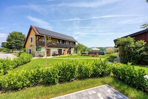 A two-story house with a sloped roof, a front porch, and a well-maintained lawn. - Merry's House w/ Pool & Sauna (Črnomelj)