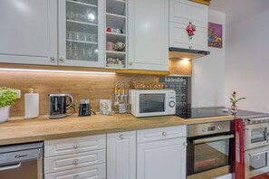 A kitchen with white cabinets, a microwave, a coffee maker, and a stove. - Merry's House w/ Pool & Sauna (Črnomelj)