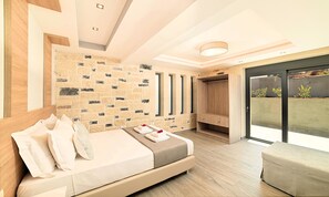 A modern bedroom with a stone wall, a large bed, a built-in wardrobe, and a sliding glass door to a balcony. - Moonlight Villa Heated Pool (Georgioupoli)