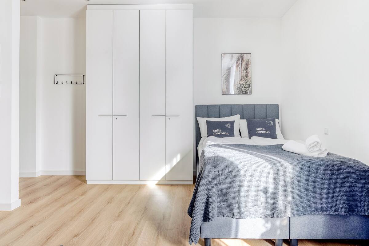 A bedroom with a bed, a wardrobe, and a painting on the wall.