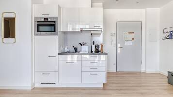 Una cuina moderna amb armaris blancs, un forn Bosch i un frigorífic d'acer inoxidable.